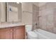 Bathroom features a shower over tub with neutral tile, a granite-topped vanity with wood cabinets and a neutral color scheme at 7668 Friendly Breeze Ct, Las Vegas, NV 89123