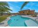 Sparkling in-ground pool and spa surrounded by green turf, desert landscaping, and a covered patio at 7668 Friendly Breeze Ct, Las Vegas, NV 89123