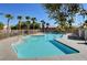 Community pool with clear blue water is surrounded by a fence and palm trees on a sunny day at 8801 Duncan Barrel Ave # 103, Las Vegas, NV 89178