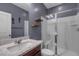Bathroom features a shower with glass doors, a marble vanity, wood shelves, and blue-gray walls at 9917 Fletcher Peak Ave, Las Vegas, NV 89178