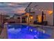 Inviting backyard featuring a sparkling pool, covered patio, stylish furniture, and ambient string lights at 9917 Fletcher Peak Ave, Las Vegas, NV 89178