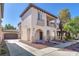 Two-story stucco home with a tile roof, arched entryway, balcony and manicured landscaping at 10345 Howling Coyote Ave, Las Vegas, NV 89135
