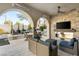 Covered patio with brick fireplace, TV, outdoor seating, and a view of the landscaped backyard at 10717 Beringer Dr, Las Vegas, NV 89144