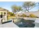 Backyard pool with waterfall feature, surrounded by lush landscaping, and desert greenery at 10717 Beringer Dr, Las Vegas, NV 89144