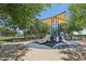 Community playground featuring a shaded play structure with slides, benches, and mature trees at 11707 Longworth Rd, Las Vegas, NV 89135