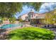 Beautiful backyard with a sparkling pool, green lawn, and mature trees at 1553 Ravanusa Dr, Henderson, NV 89052