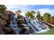Scenic water feature cascading down rocks with lush landscaping and palm trees at 174 Cabo Cruces Dr, Henderson, NV 89011