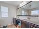 Bathroom with double sinks, dark wood cabinetry, a large framed mirror, and a view to the backyard at 3237 Mist Effect Ave, Henderson, NV 89044