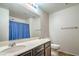 A well-lit bathroom featuring a single sink vanity, a toilet, and a shower with a blue curtain at 3237 Mist Effect Ave, Henderson, NV 89044