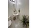 Charming powder room with a pedestal sink, oval mirror, and modern fixtures and white tile floors at 369 Stone Fly Rd, North Las Vegas, NV 89032