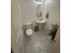 Stylish powder room with a pedestal sink, oval mirror, toilet and white tile flooring at 369 Stone Fly Rd, North Las Vegas, NV 89032