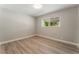Neutral bedroom features wood-look flooring, neutral paint, and a window with a view at 5245 Hillman Ave, Las Vegas, NV 89142