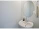 Clean, minimalist bathroom with a pedestal sink, modern faucet, and an oval mirror at 7499 Lodano Ave, Las Vegas, NV 89113