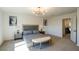 Well-lit bedroom with modern lighting fixture, soft carpet, neutral walls, and view to the adjacent hallway at 7499 Lodano Ave, Las Vegas, NV 89113