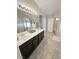 Bathroom featuring dual sinks, a large mirror, and tile flooring leading to the tub and shower at 8340 Winterchase Pl, Las Vegas, NV 89143