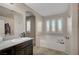 Bright bathroom featuring a vanity with granite countertop, and a soaking tub at 9327 S Chieftain St, Las Vegas, NV 89178