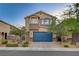 Traditional two-story home featuring a blue garage door and front yard landscaping at 9327 S Chieftain St, Las Vegas, NV 89178