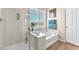 Bright bathroom featuring a corner tub, shower, and window, with wood-look floors at 9872 Chief Sky St, Las Vegas, NV 89178