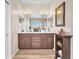 Bathroom vanity with dual sinks, wood-look floors and framed mirror at 9872 Chief Sky St, Las Vegas, NV 89178