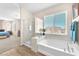Bright bathroom featuring a corner tub, shower, and window, with wood-look floors at 9872 Chief Sky St, Las Vegas, NV 89178