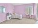 Bright bedroom features mauve walls, carpet, desk and bed with lots of natural light at 9872 Chief Sky St, Las Vegas, NV 89178
