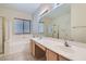 Bathroom with a double sink vanity, large mirror, bathtub, and glass-enclosed shower at 10667 Casa Bianca St, Las Vegas, NV 89141