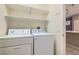 Bright laundry room with white washer, dryer, and shelving for organized storage solutions at 10667 Casa Bianca St, Las Vegas, NV 89141