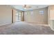 Spacious living room with a ceiling fan, neutral walls, carpet flooring, and sliding door access to the patio at 10667 Casa Bianca St, Las Vegas, NV 89141