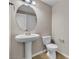 Powder room with pedestal sink, toilet, round mirror, and neutral wall paint at 11014 Great Sioux Rd, Las Vegas, NV 89179