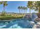 Backyard pool with rock waterfall, surrounded by lush palm trees and manicured landscaping at 151 Cliff Valley Dr, Las Vegas, NV 89148