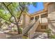 Exterior view of a building showing stairs to upper units, mature trees, and ample parking at 1557 Lake Placid Ter # 1557, Henderson, NV 89014