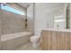 The neutral toned bathroom includes a tub, tiled walls, window, and modern vanity at 1600 Pleasant Bay Ct, Henderson, NV 89011