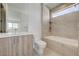 Modern bathroom with gray tiled walls, a tub, and a floating light wood vanity at 1600 Pleasant Bay Ct, Henderson, NV 89011