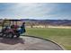 A picturesque golf course scene with a golf cart in the foreground and rolling hills providing a stunning backdrop for golf at 1725 Cypress Manor Dr, Henderson, NV 89012