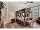 Spacious main bedroom with a dark wood canopy bed, hardwood floors, and bright, natural light at 1725 Cypress Manor Dr, Henderson, NV 89012