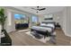 Digitally staged bedroom showcasing a bed, dresser, nightstands and wood-look floors illuminated by natural light at 177 Rocky Star St, Henderson, NV 89012