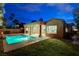 Aerial view of a backyard at dusk featuring pool, desert landscaping, lawn and covered patio at 2074 Sutton Way, Henderson, NV 89074