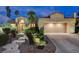 Exterior dusk view featuring lush landscaping, desert landscaping and an attached two car garage at 2074 Sutton Way, Henderson, NV 89074