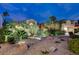 Dusk view of a well-maintained property featuring desert landscaping, lighting and mature palm trees at 2074 Sutton Way, Henderson, NV 89074