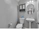 Small bathroom with toilet, pedestal sink, gray walls, and cabinet over toilet at 3964 Irvin Ave, Las Vegas, NV 89141