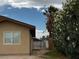 View of the side yard, showing the house exterior, chain link gate, and lush bushes at 4189 Studio St, Las Vegas, NV 89115