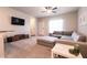 Bright living room featuring carpet, a gray sectional, ceiling fan, and a wall-mounted television at 7302 Sunray Point St, North Las Vegas, NV 89084