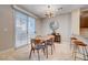 Cozy dining area with modern light fixture, table, and chairs, complemented by tile flooring and a sliding glass door at 8719 Villa Ariel Ln, Las Vegas, NV 89147