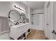 Bright bathroom featuring a double sink vanity, round mirrors, and wood-look flooring at 1001 Domnus Ln # 201, Las Vegas, NV 89144