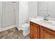 Bathroom with white walls, toilet, wood vanity, and walk-in shower with glass door at 10056 Cranbrook Falls Ct, Las Vegas, NV 89148