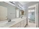 Bathroom featuring dual sinks, a large mirror, and walk-in shower at 10241 Regents Cross Pl, Las Vegas, NV 89144