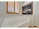 Close-up of a bathtub with a window and a fireplace at 11444 Steponia Bay St, Las Vegas, NV 89141