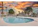 Community pool with a clean white fence, blue water, and desert landscaping with a vibrant sunset at 1300 Pinto Rock Ln # 201, Las Vegas, NV 89128
