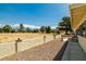 Backyard featuring desert landscaping, a low privacy wall, and views of mature trees in the distance at 1320 Daytona St, Pahrump, NV 89048