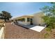 Exterior shot showcasing the patio, neutral paint, desert landscaping, and a backdrop of mature trees at 1320 Daytona St, Pahrump, NV 89048